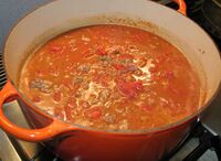 Canned tomatoes and canned, unflavored tomato sauce have been added and are ready to begin cooking, along with a little red wine.